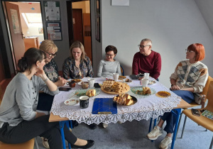 Opiekunowie siedzący wokół stołu z poczęstunkiem