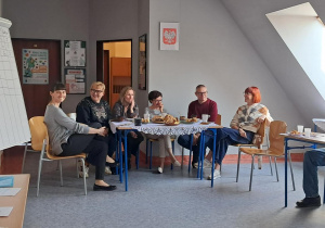 Opiekunowie siedzący wokół stołu z poczęstunkiem