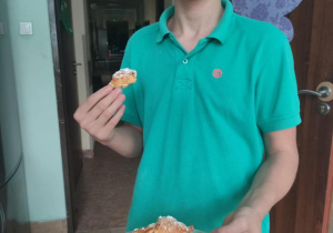 Uczeń trzyma talerz z gotowymi rogalikami