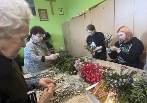 Uczennice przy stole układają bukiety z palemek