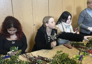 Uczennice przy stole układają bukiety z palemek