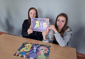 Dwie uczennice prezentują ułożone puzzle