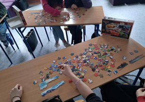 Stolik z rozrzuconymi puzzlami w trakcie układania