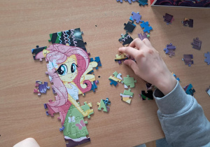 Stolik z rozrzuconymi puzzlami w trakcie układania