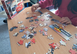 Stolik z rozrzuconymi puzzlami w trakcie układania