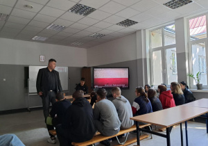 Uczniowie w sali oglądają prezentację multimedialną na ekranie