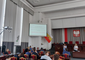 Sala w urzędzie wypełniona uczniami i prowadzący spotkanie
