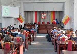 Sala w urzędzie wypełniona uczniami i prowadzący spotkanie